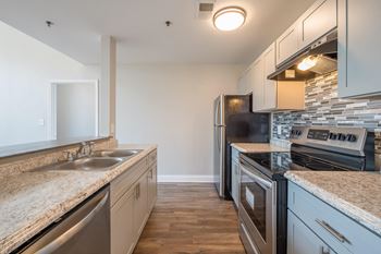 an empty kitchen with granite counter tops and stainless steel appliances at Crogman School Lofts, Atlanta, 30315
